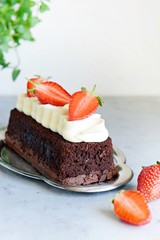 Chocolate brownie with airy vanilla cream and fresh strawberries. Chocolate cake with cream and fresh berries. Tea dessert