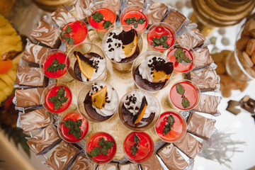Fototapeta na wymiar desserts with fruits, mousse, biscuits. Different types of sweet pastries, small colorful sweet cakes, macaron, and other desserts in the sweet buffet. candy bar for birthday