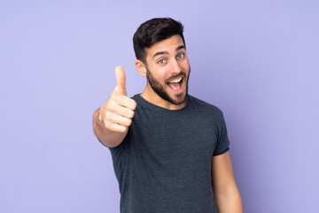 Caucasian handsome man with thumbs up because something good has happened over isolated purple...