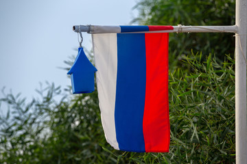 Russian tree color flag with a small house and sea shore foliage. Russia home concept.