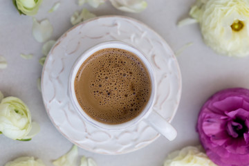 Springtime concept. A cup of coffee and white ranunculus flowers
