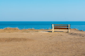 Fototapeta na wymiar Empty bench on sea shore in steppe. Sea view from mountain. Travel, relax or loneliness concept