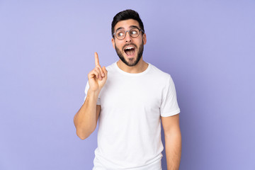Caucasian handsome man over isolated background intending to realizes the solution while lifting a...