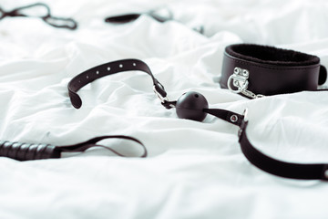 selective focus of bdsm leash and gag on white bedding