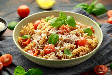 Healthy Chicken, fusilli pasta with tomatoes, basil and parmesan cheese. on wooden table.