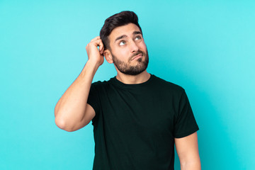 Caucasian handsome man isolated on blue background having doubts and with confuse face expression - obrazy, fototapety, plakaty
