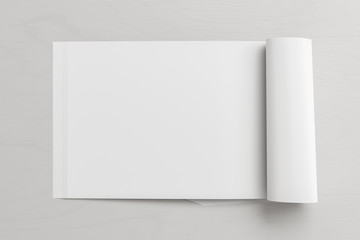 Blank horizontal left magazine page. Workspace with folded magazine mock up on white desk. View above. 3d illustration