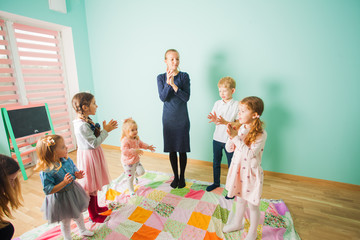 Children sing a song with a teacher together. Kids in a nursery.