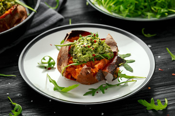 Baked Sweet potato boats stuffed with avocado guacamole and wild rocket sprinkled with nigella seeds