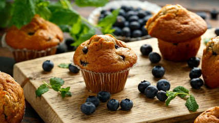 Blueberries muffins, cupcake with mint and berry on wooden board.