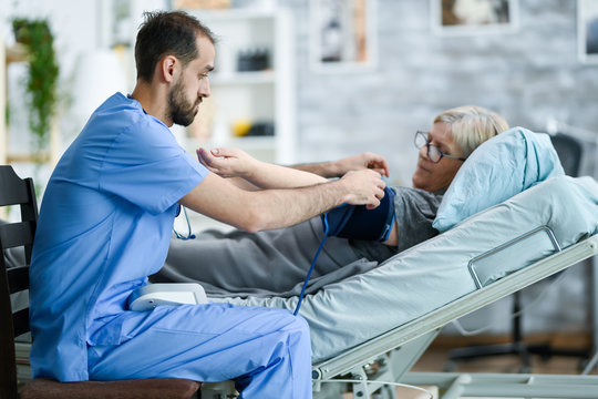 Male caretaker in a nursing home taking bood pressure