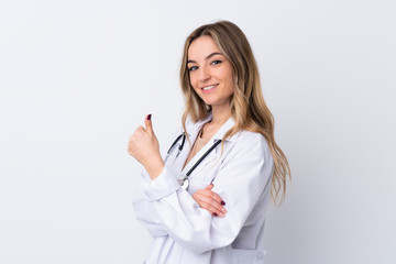 Young woman over isolated white background wearing a doctor gown and with thumb up