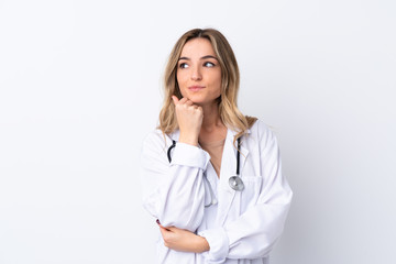 Young woman over isolated white background wearing a doctor gown and thinking