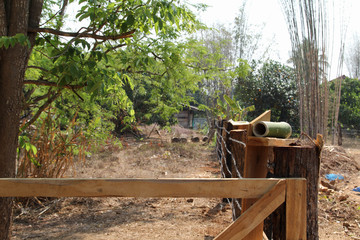 The barbed wire fence with logs of Thai style countryside home.
