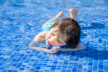 portrait of a pretty little girl playing in a swimming pool