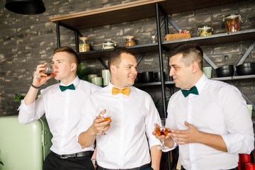Fototapeta na wymiar three men in a white shirt drink whiskey in glasses in a loft apartment