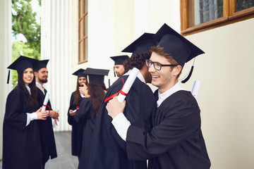 Female graduates with diplomas in their hands hugging