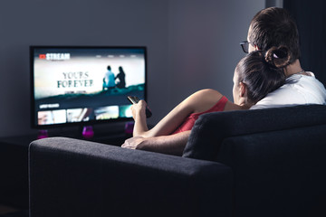 Movie stream service on smart tv. Couple watching series online. Woman choosing film or new season...