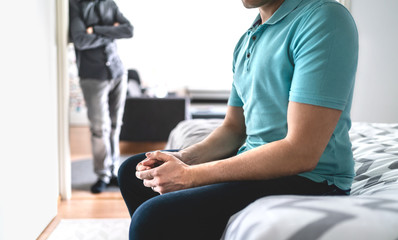 Obraz premium Gay couple in fight. Sad man in argument. Male friends or brothers in conflict. Stress or crisis in relationship. Infidelity and cheating or jealousy and mistrust. Upset guy sitting on bed at home.