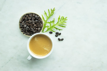 Top view, Closed up fresh mug coffee and green leave, beans in wooden tray on grey background, this menu made from dark roasted coffee.