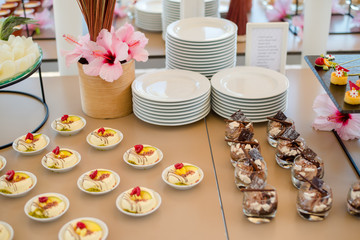 The catering wedding buffet. Wedding reception dessert table with delicious decorated white cupcakes with berries closeup.