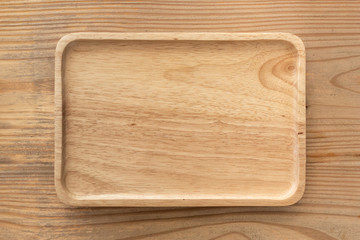 An empty wooden tray placed on a wooden table.