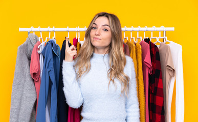 Young woman in a clothing store over isolated yellow background pointing with the index finger a great idea