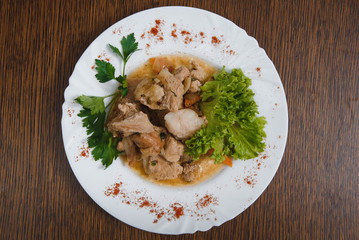 Plate of grilled beef nuggets, fried potato chips or French fries and fresh leafy green salad with cucumber on a white background