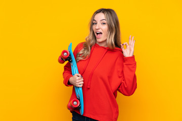 Young woman over isolated yellow background with a skate and doing OK sign