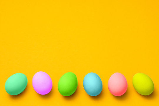 vivid colored easter eggs on a yellow background with copy space. easter background for advertisement