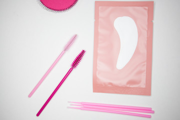  tools for eyelash extension, golden tweezers, microbrush, finished bundles, pink brushes, eye patches, on a white background