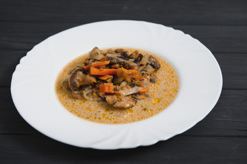 Plate with delicious mushrooms with creamy sauce on wooden background