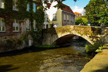 Fototapeta na wymiar Bruges, Belgium. August 2019. One of the ancient stone bridges: they characterize the place with their medieval charm. Tourists stopped to enjoy this particular point of view.