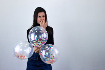 Con miedo mordiendose las uñas ballet dancer, caucasian middle age womanparty balloonsfeels fear, bits nails, isolated on gray background studio shot, black sweater, denim jacket, jeans, dark air. Pla