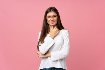 Young woman over isolated pink background with glasses and smiling