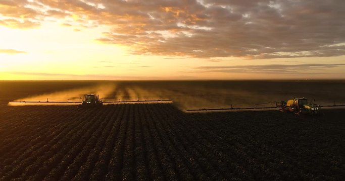 Agriculture, beautiful aerial image of machines spraying cotton plantation in the open field with beautiful sunset - Agribusiness.
