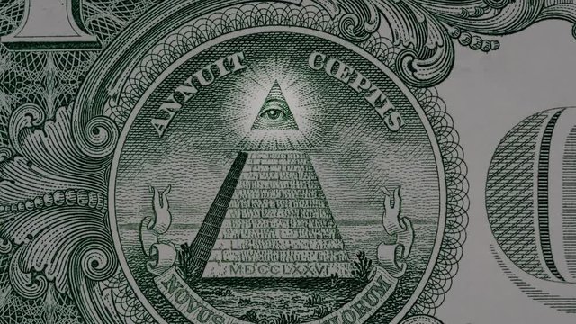 Creative 4k video of details of a 1 american dollar banknote macro closeup with a pyramid and the effect of a glowing mason eye on top. Pyramid close-up on a banknote of 1 US dollars.