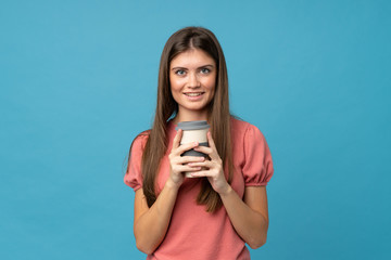 Young woman over isolated blue background holding coffee to take away