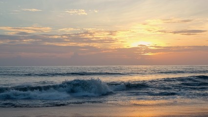Stunning sunset over the ocean with colorful clouds...Abstract nature blurred background sunset with red orange clouds in the sky over the sea.Beautiful sunset and waves on the beach.