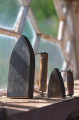 two different sized antique irons with wooden handles