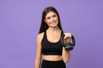 Fototapeta na wymiar Young girl woman over isolated background making weightlifting with kettlebell