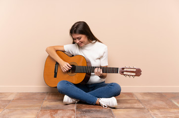 Young woman with guitar sitting on the floor