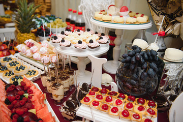 desserts with fruits, mousse, biscuits. Different types of sweet pastries, small colorful sweet cakes, macaron, and other desserts in the sweet buffet. candy bar for birthday