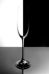 Empty champagne glass with reflection, on white and black gradient background. Club life concept.