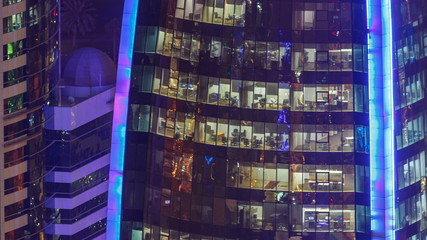 Fototapeta na wymiar Windows timelapse of the multi-storey building of glass and steel office lighting and working people within