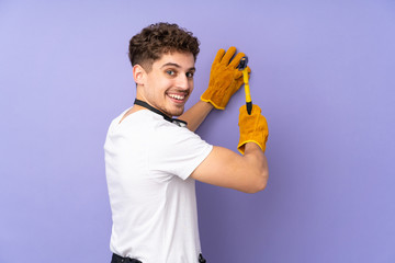 Young electrician man over isolated on purple background