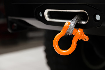 A towing winch with a clevis and a loop on a metal cable mounted on a car for pulling out and...