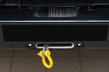 A towing winch with a shackle and a loop on a metal cable mounted on a car for pulling out and evacuating vehicles. Overcoming off-road and extreme racing.