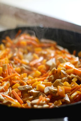 Stir frying carrot, red kuri squash and portobello mushrooms. Selective focus.