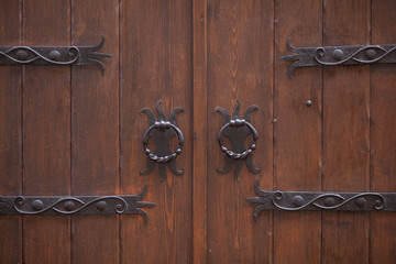 Close up of large closed wooden gate with carved iron handles